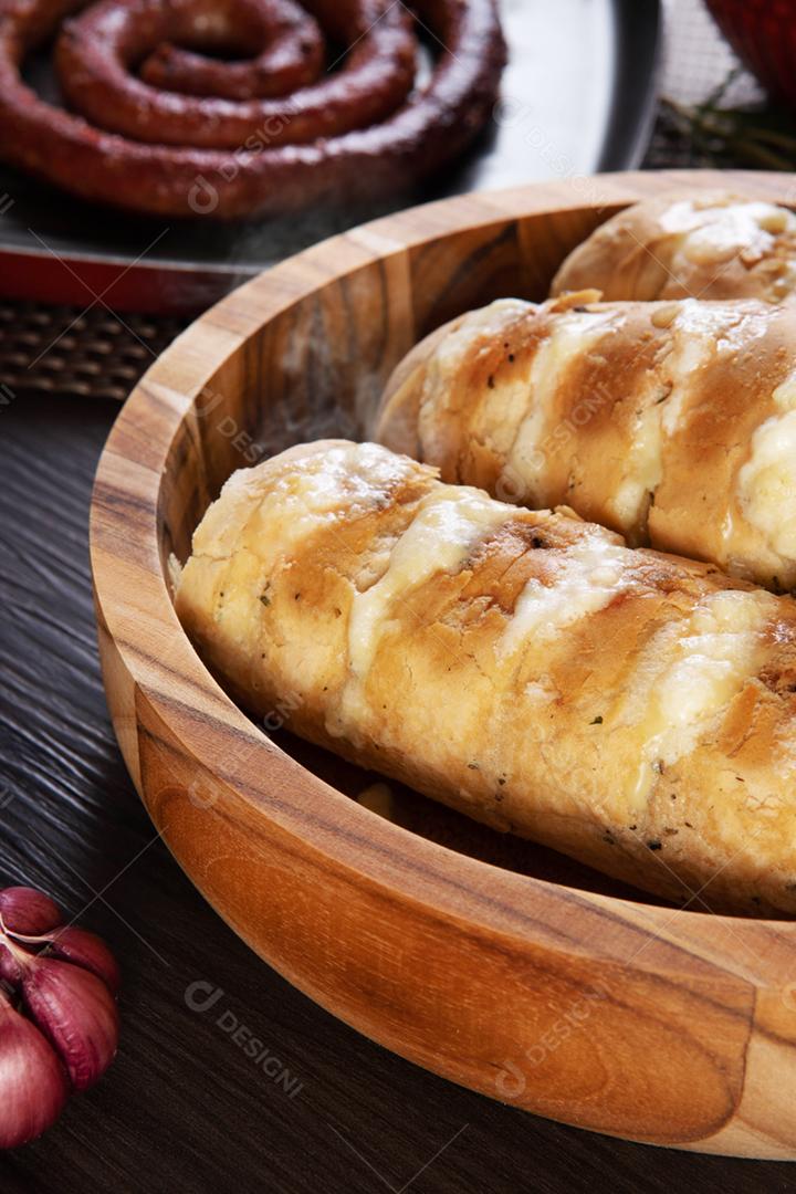 Pão de alho em um prato vermelho na mesa de churrasco com salsicha,