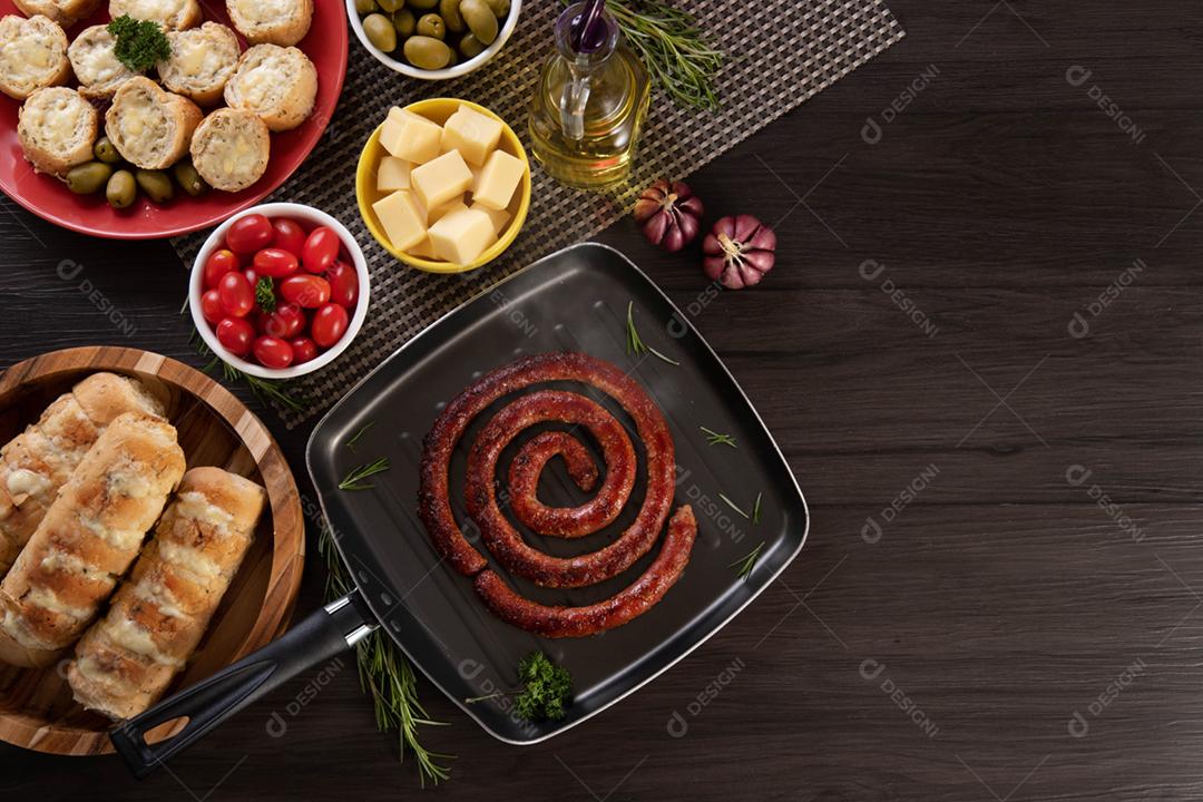 Linguiça assada com pão de salsicha e alho em um prato vermelho na mesa de churrasco wi