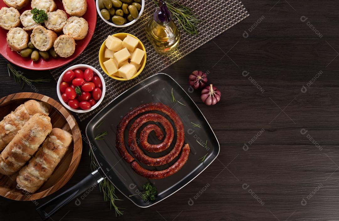 Linguiça assada com pão de salsicha e alho em um prato vermelho na mesa de churrasco wi