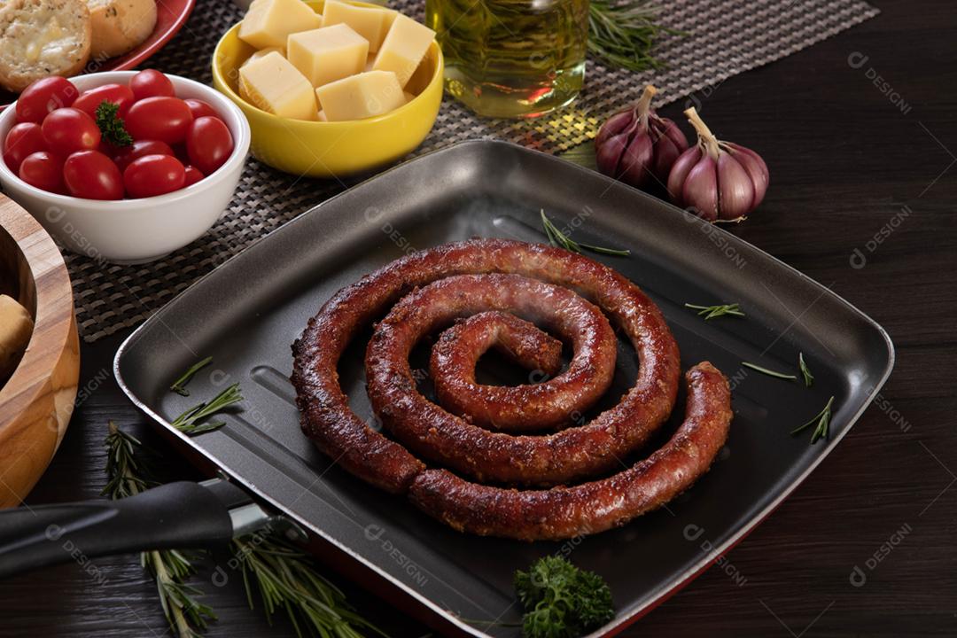 Linguiça assada com pão de salsicha e alho em um prato vermelho na mesa de churrasco wi