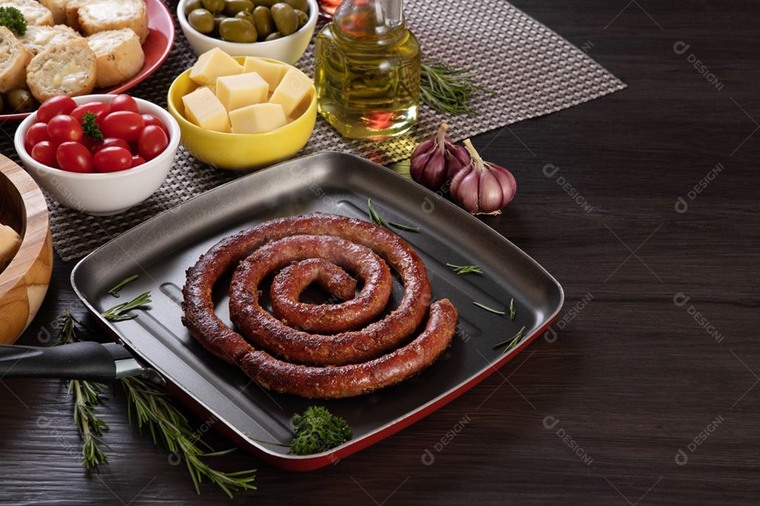 Linguiça assada com pão de salsicha e alho em um prato vermelho na mesa de churrasco wi