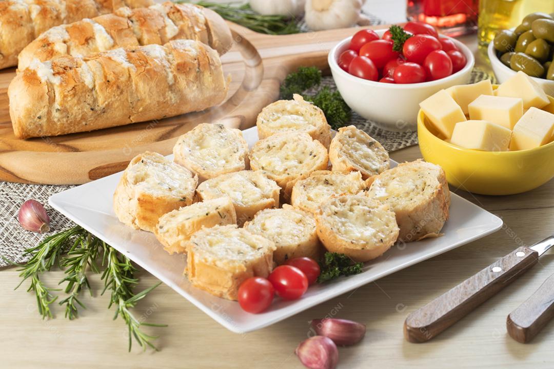 Pão de alho em um prato vermelho na mesa de churrasco com salsicha,