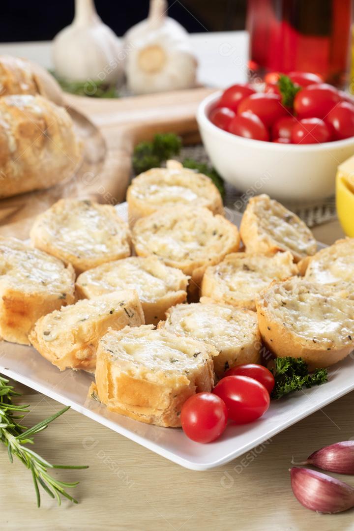 Pão de alho em um prato vermelho na mesa de churrasco com salsicha,