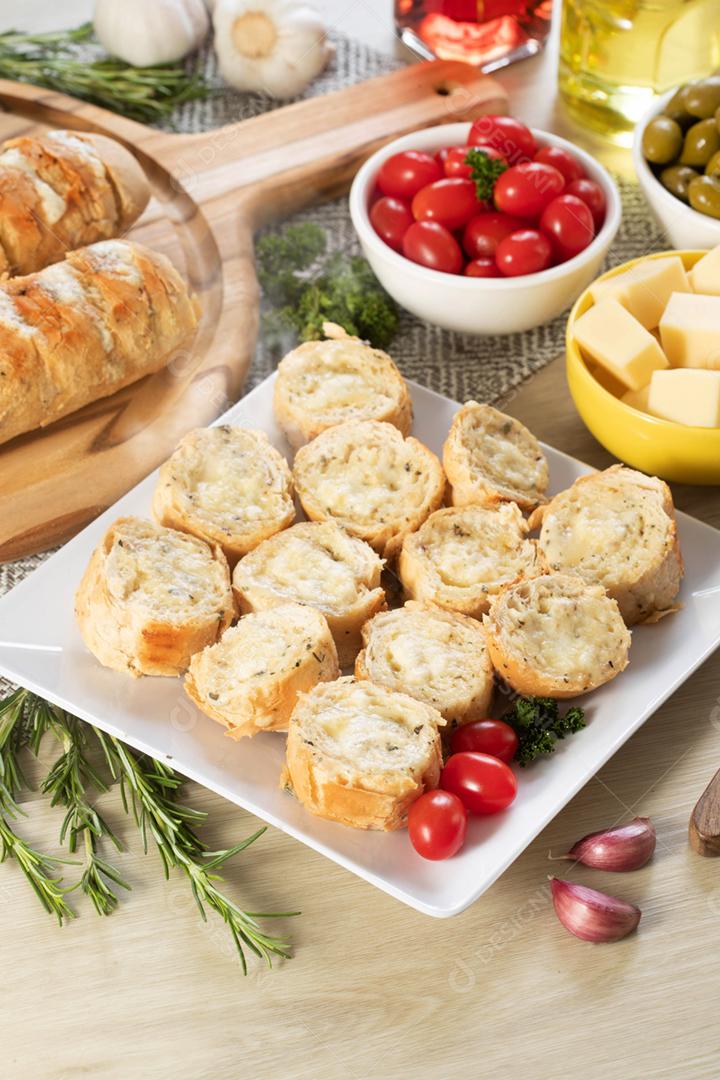 Pão de alho em um prato vermelho na mesa de churrasco com salsicha,