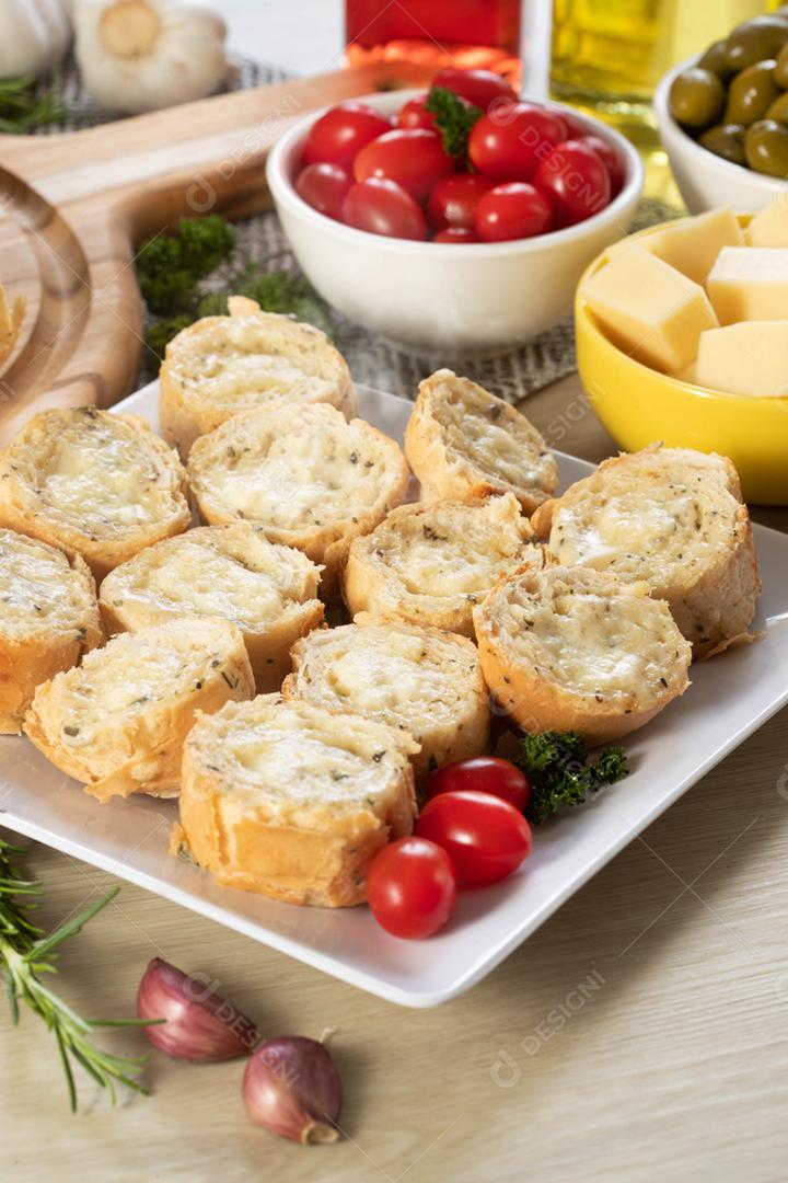 Pão de alho em um prato vermelho na mesa de churrasco com salsicha,