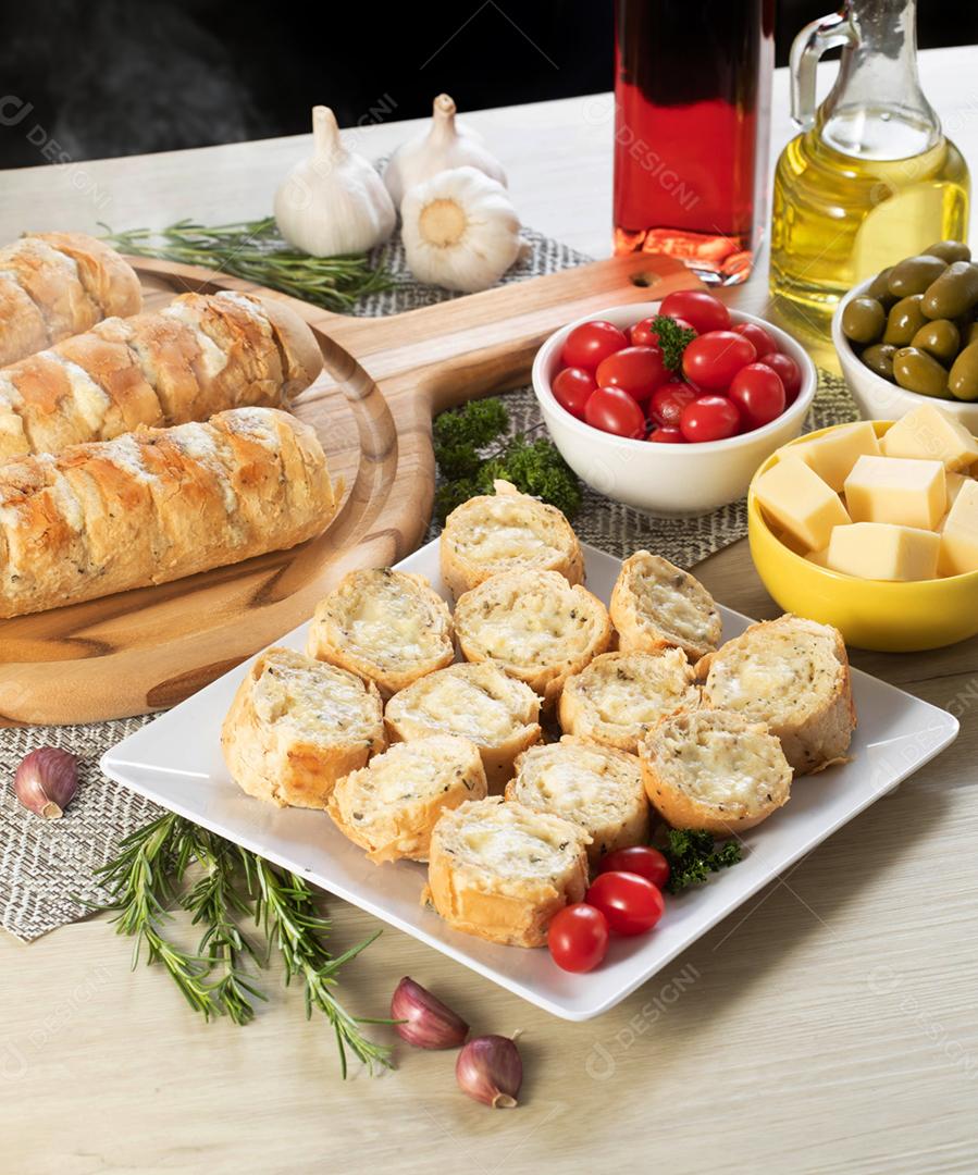 Pão de alho em um prato vermelho na mesa de churrasco com salsicha,