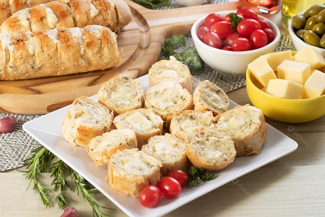 Pão de alho em um prato vermelho na mesa de churrasco com salsicha,