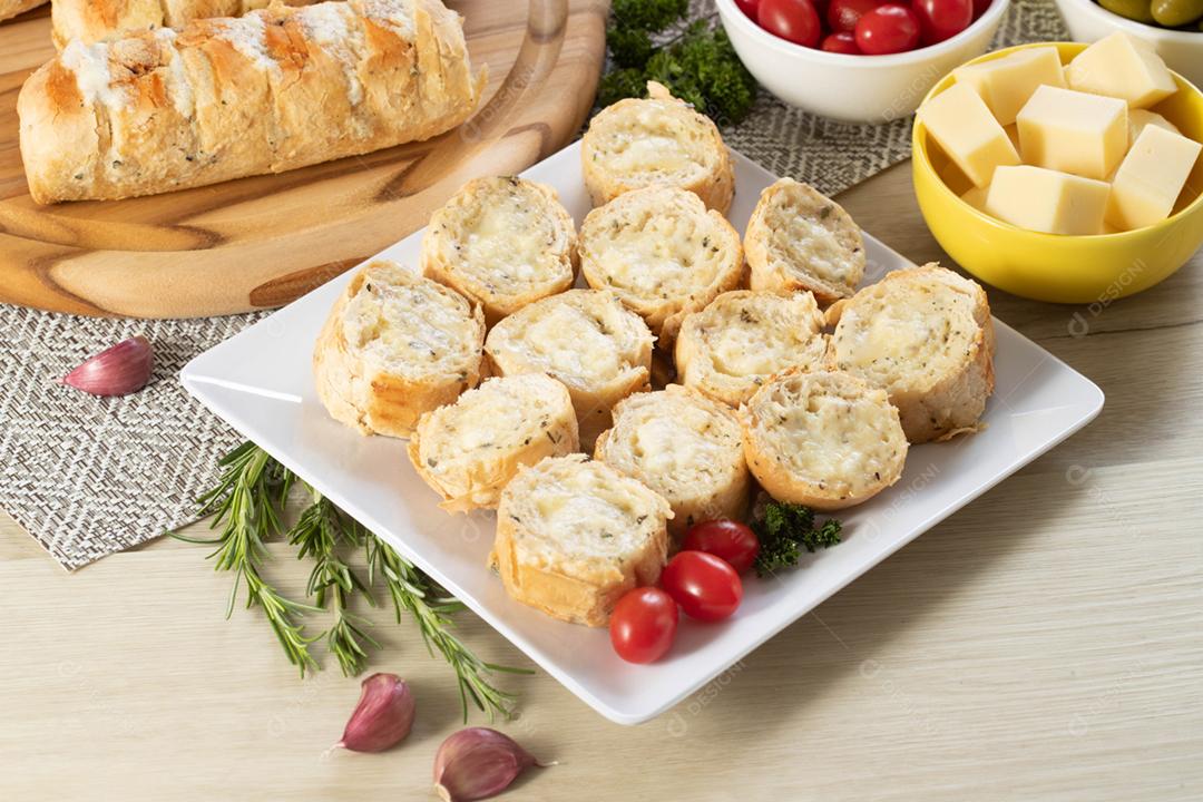 Pão de alho em um prato vermelho na mesa de churrasco com salsicha,