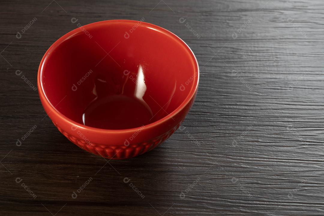 Tigela vermelha sobre fundo de madeira.