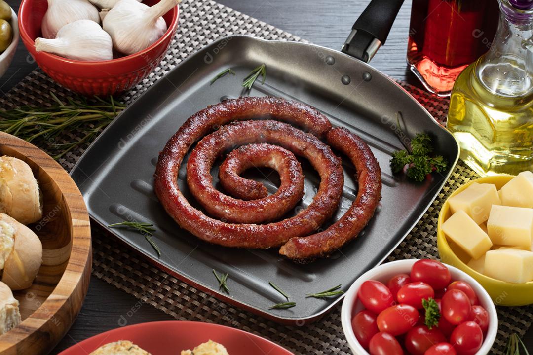 Linguiça assada com pão de salsicha e alho em um prato vermelho na mesa de churrasco wi