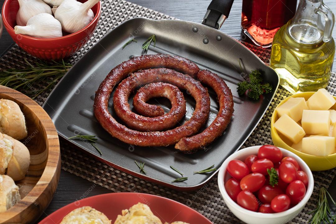 Linguiça assada com pão de salsicha e alho em um prato vermelho na mesa de churrasco wi