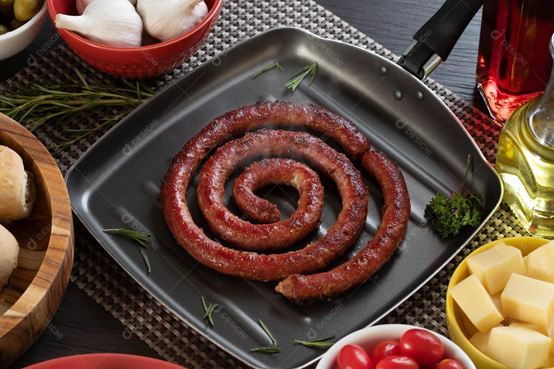 Linguiça assada com pão de salsicha e alho em um prato vermelho na mesa de churrasco wi