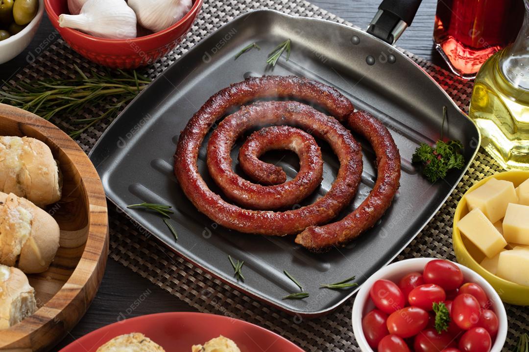 Linguiça assada com pão de salsicha e alho em um prato vermelho na mesa de churrasco wi