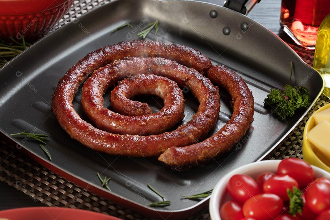 Linguiça assada em um prato vermelho na mesa de churrasco wi