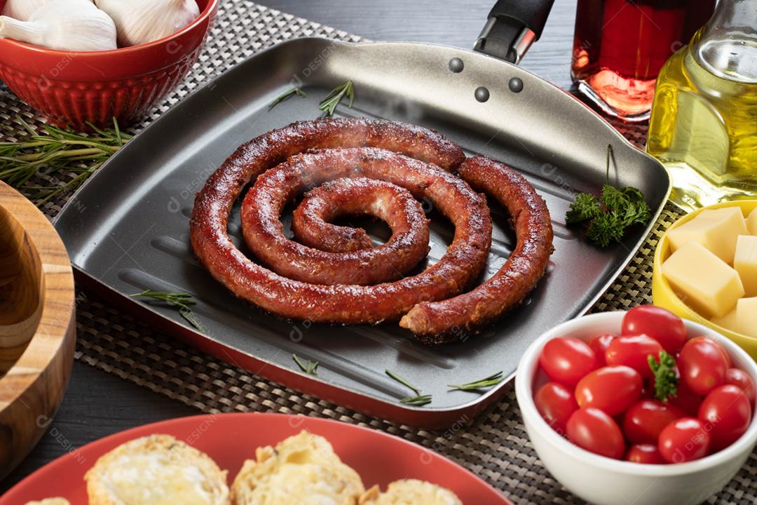 Linguiça assada com pão de salsicha e alho em um prato vermelho na mesa de churrasco wi