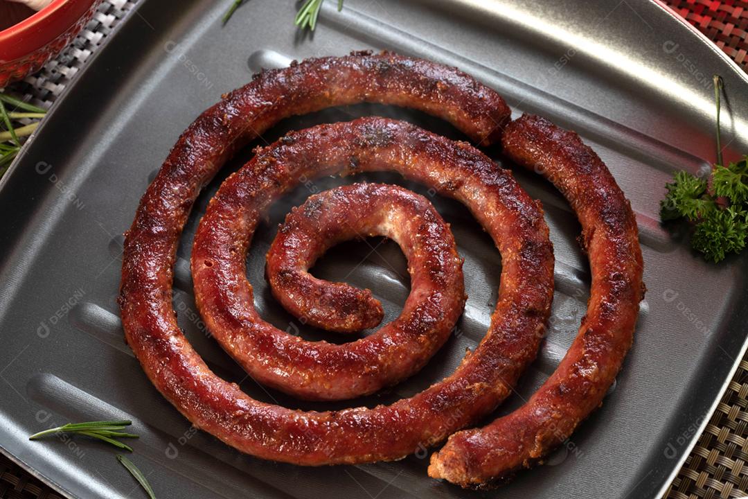 Linguiça assada com pão de salsicha e alho em um prato vermelho na mesa de churrasco wi