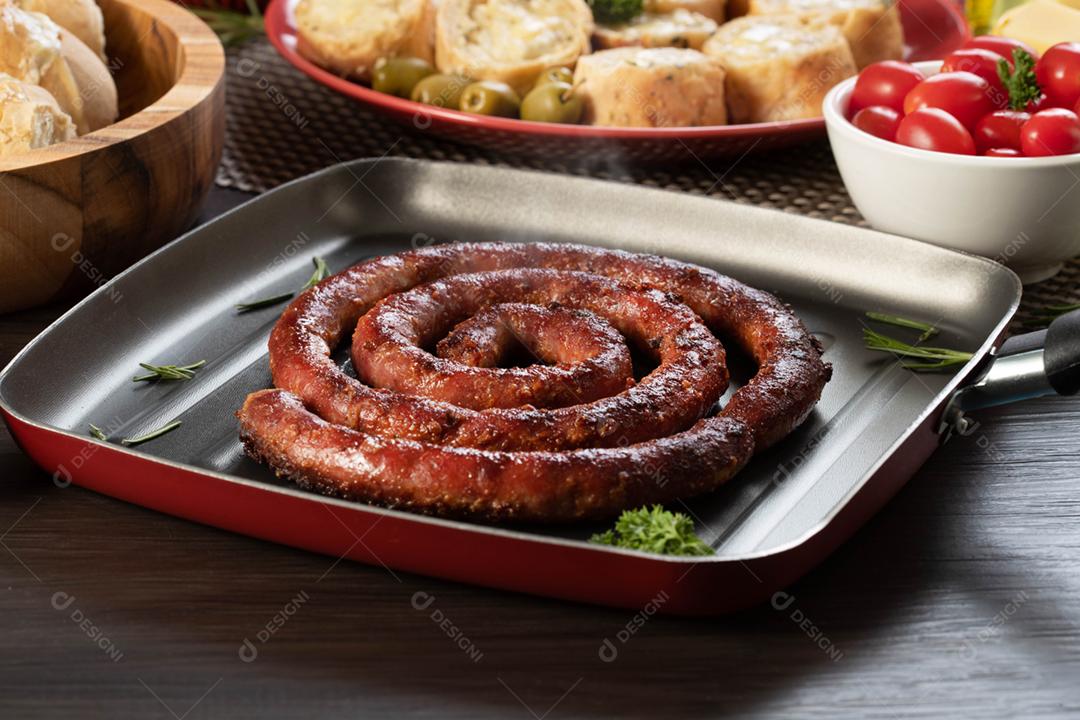 Linguiça assada com pão de salsicha e alho em um prato vermelho na mesa de churrasco wi