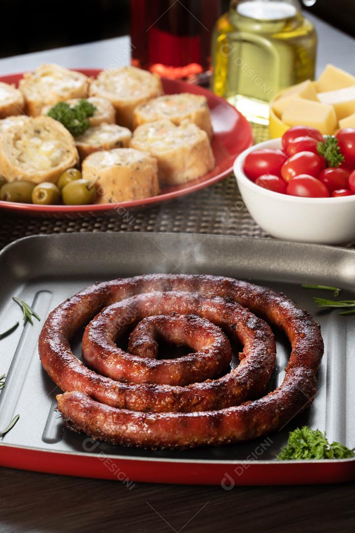 Linguiça assada com pão de salsicha e alho em um prato vermelho na mesa de churrasco wi