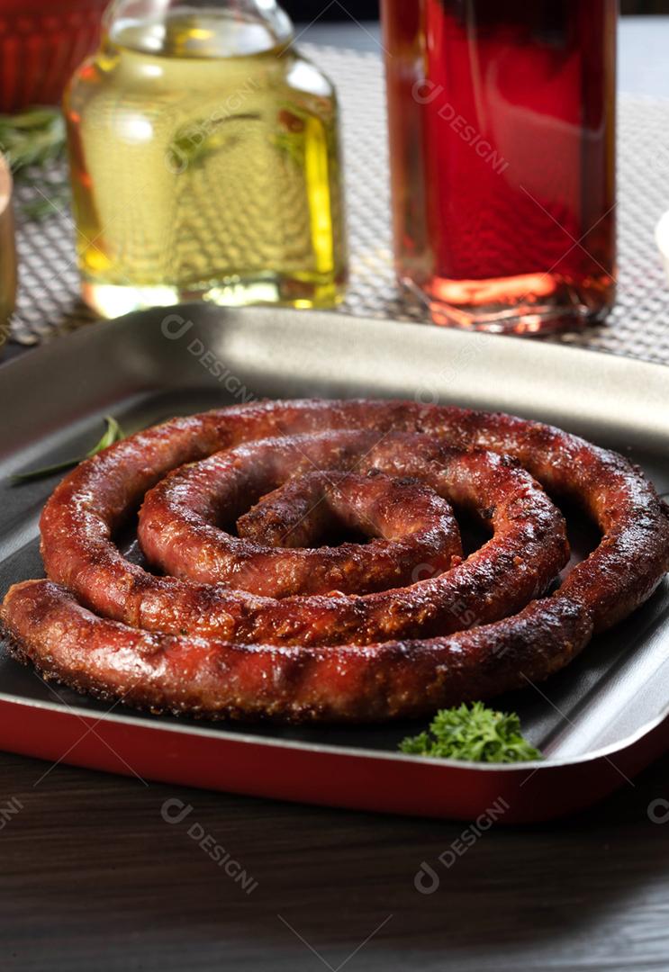 Linguiça assada com pão de salsicha e alho em um prato vermelho na mesa de churrasco wi