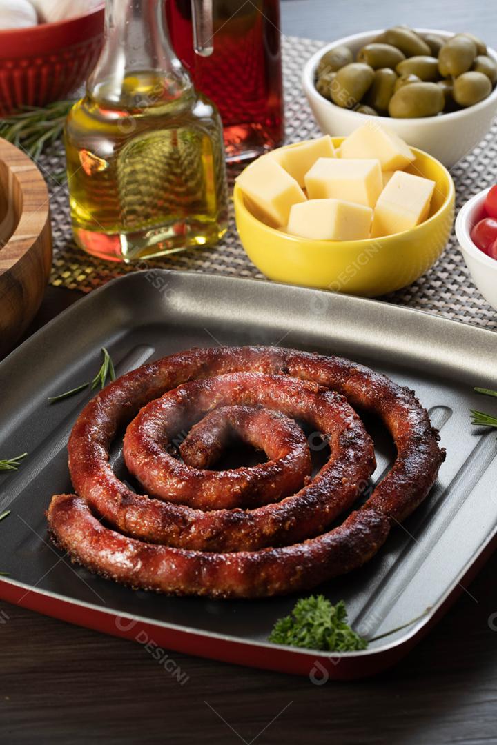 Linguiça assada com pão de salsicha e alho em um prato vermelho na mesa de churrasco wi