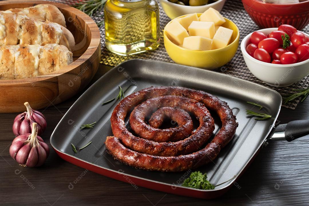 Linguiça assada com pão de salsicha e alho em um prato vermelho na mesa de churrasco wi