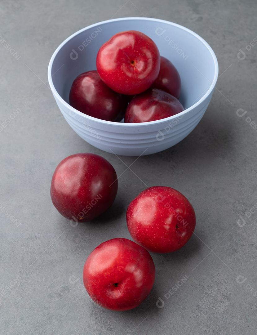 Ameixas em uma tigela sobre fundo de pedra.