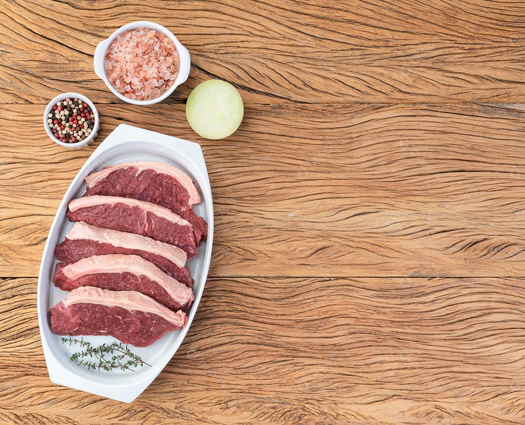 Fatias de lombo de tira crua sobre chapa branca com temperos.