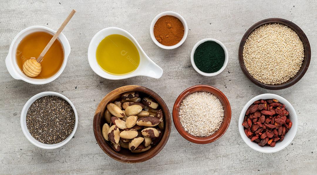 Super alimentos variados sobre fundo de pedra. Chia, quinoa, aveia, linhaça, mel, espirulina e outros.