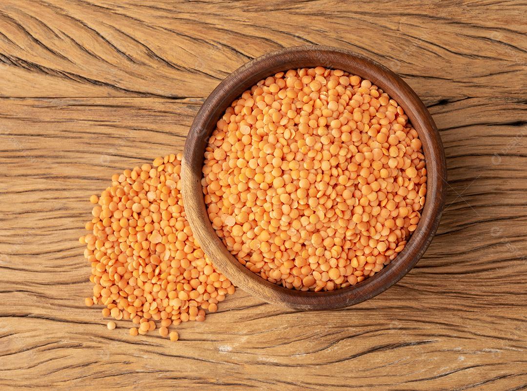 Lentilha laranja em uma tigela sobre a mesa de madeira.