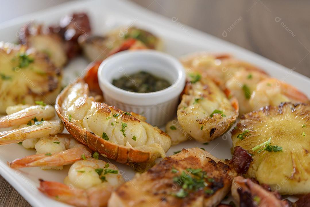 Frutos do mar. Lagosta, camarão, polvo e peixe em tigela branca na mesa de madeira. comida brasileira.