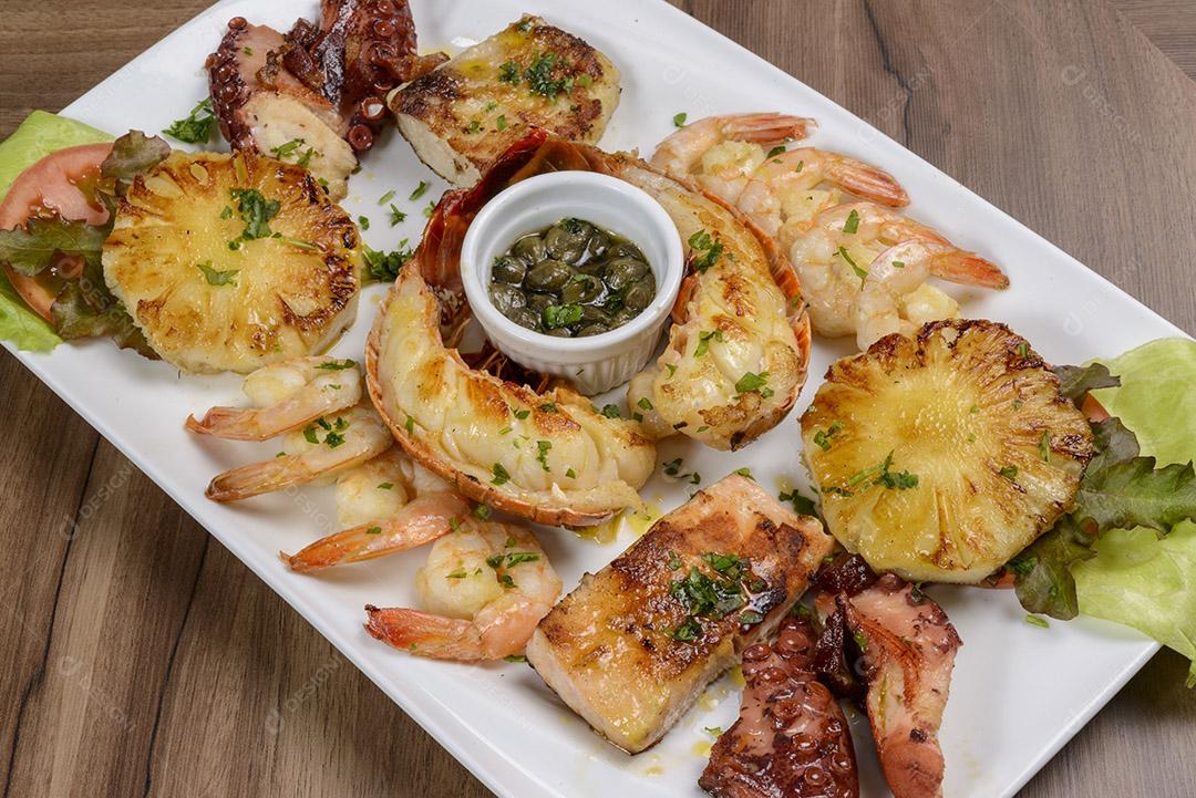 Frutos do mar. Lagosta, camarão, polvo e peixe em tigela branca na mesa de madeira. comida brasileira.