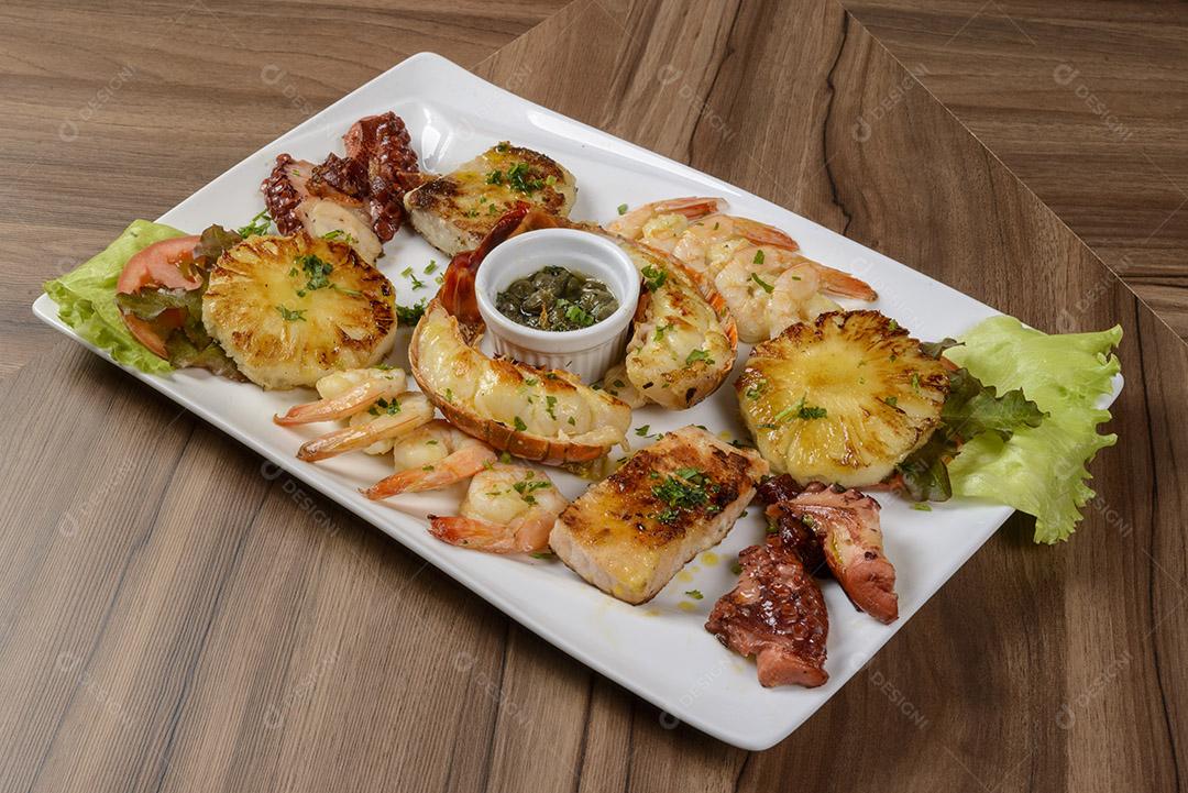 Frutos do mar. Lagosta, camarão, polvo e peixe em tigela branca na mesa de madeira. comida brasileira.