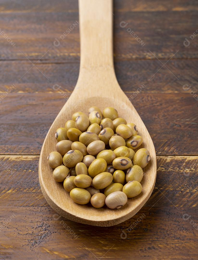Feijão amarelo em uma colher sobre a mesa de madeira.