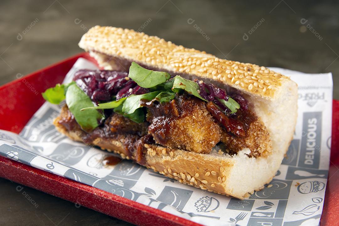 Sanduíche de frango frito, cebola e salada.