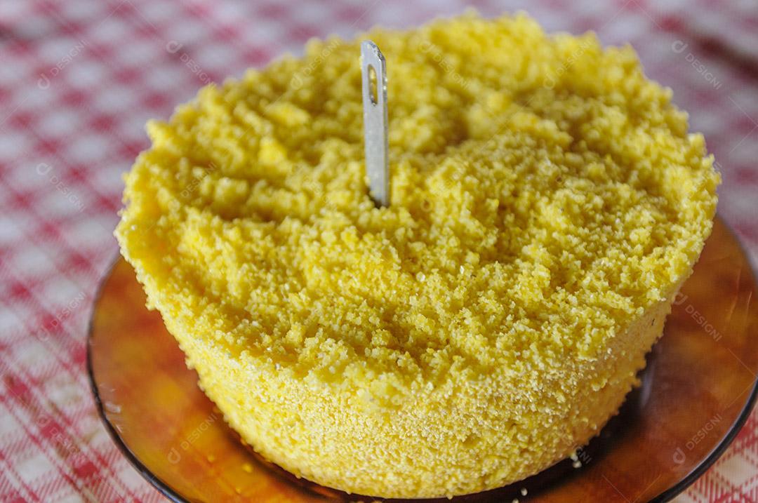 Cuscuz de milho na mesa com toalha de mesa vermelha e branca.