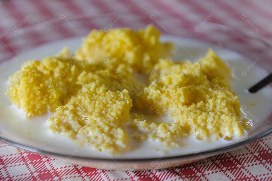 Cuscuz de milho com leite na mesa com toalha de mesa vermelha e branca.