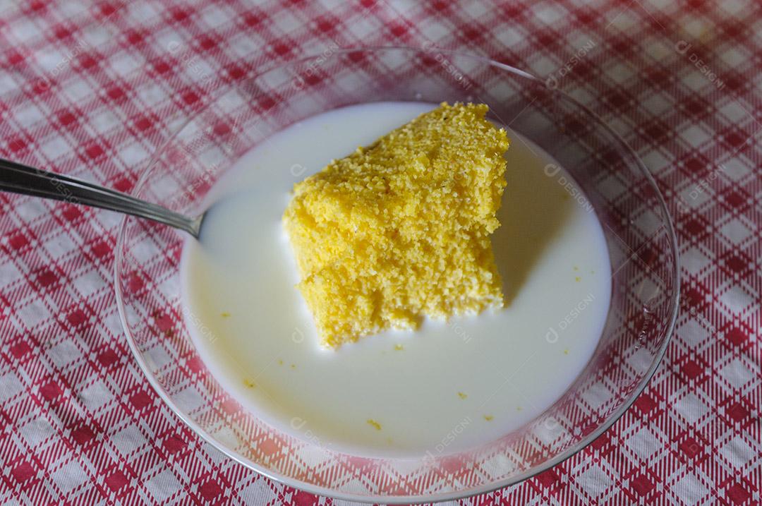 Cuscuz de milho com leite na mesa com toalha de mesa vermelha e branca.