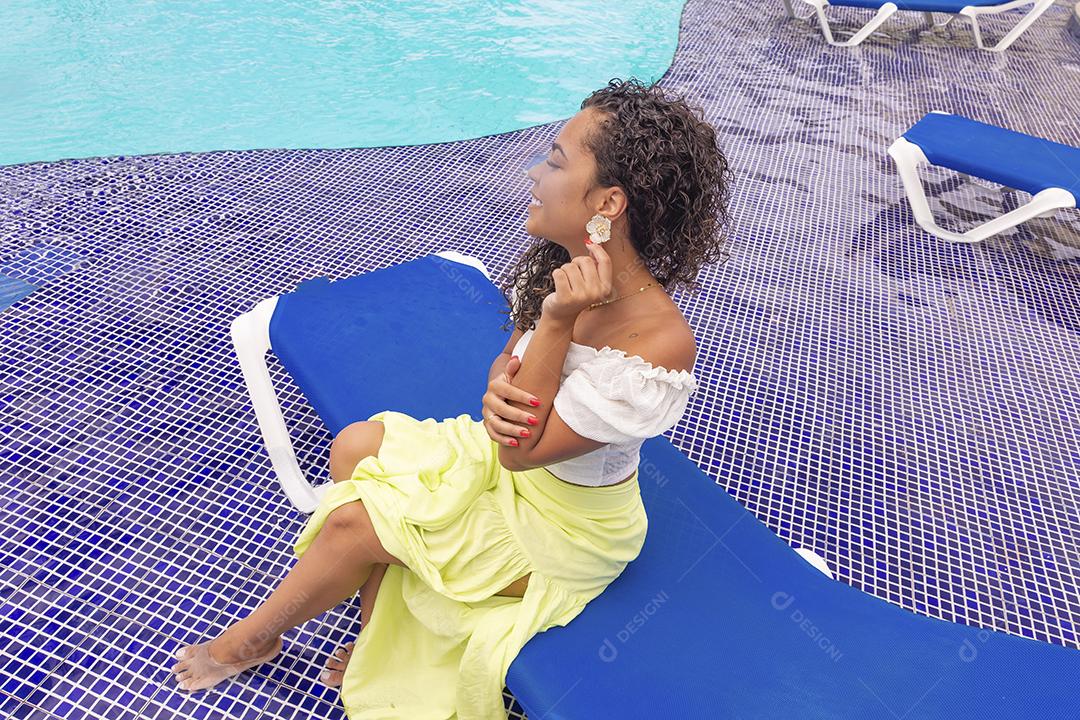 Mulher afro de férias curtindo a piscina do hotel.