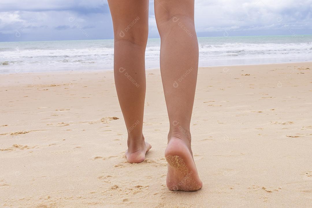 Pés femininos andando na areia da praia