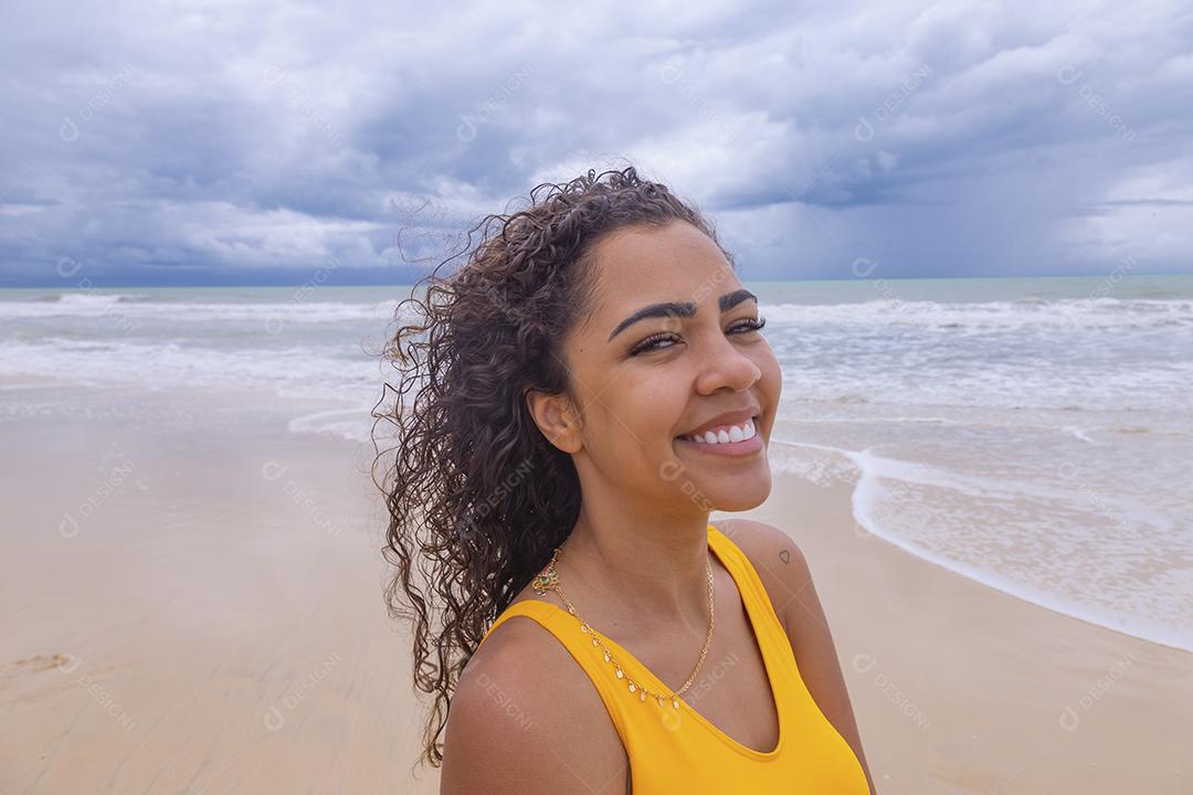 Morena jovem bonita, cabelo encaracolado, biquíni, praia. Férias de férias de verão afro-americanas.