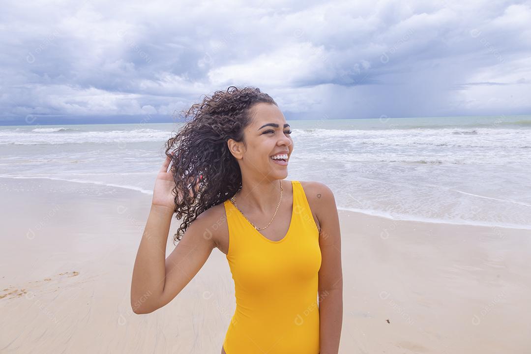 Morena jovem bonita, cabelo encaracolado, biquíni, praia. Férias de férias de verão afro-americanas.