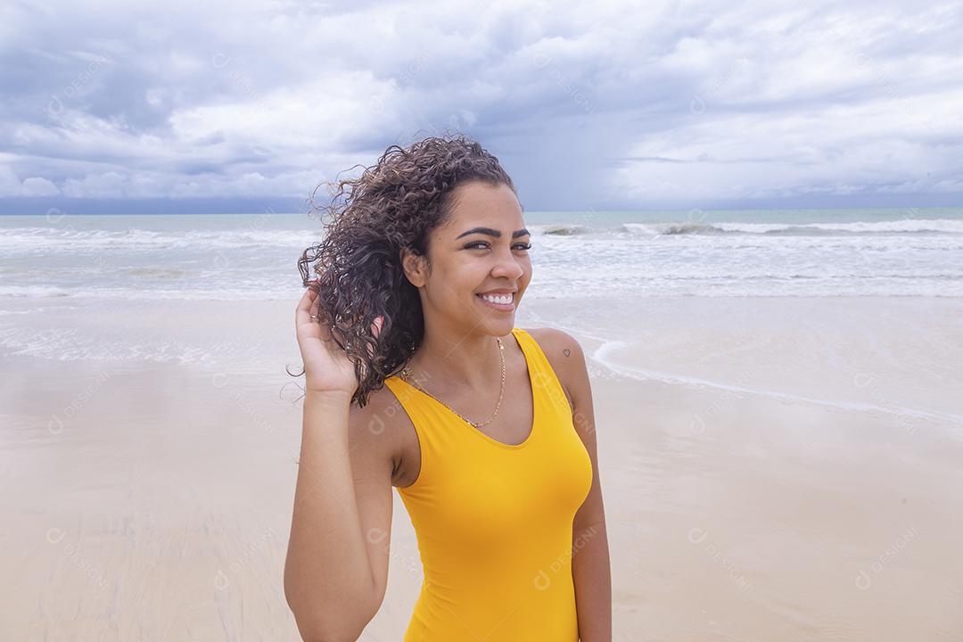 Morena jovem bonita, cabelo encaracolado, biquíni, praia. Férias de férias de verão afro-americanas.