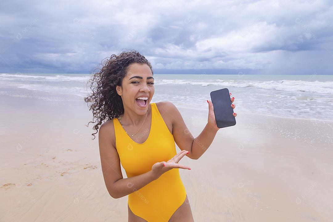 férias de verão, tecnologia e conceito de internet. Mulher afro com celular com tela em branco na praia