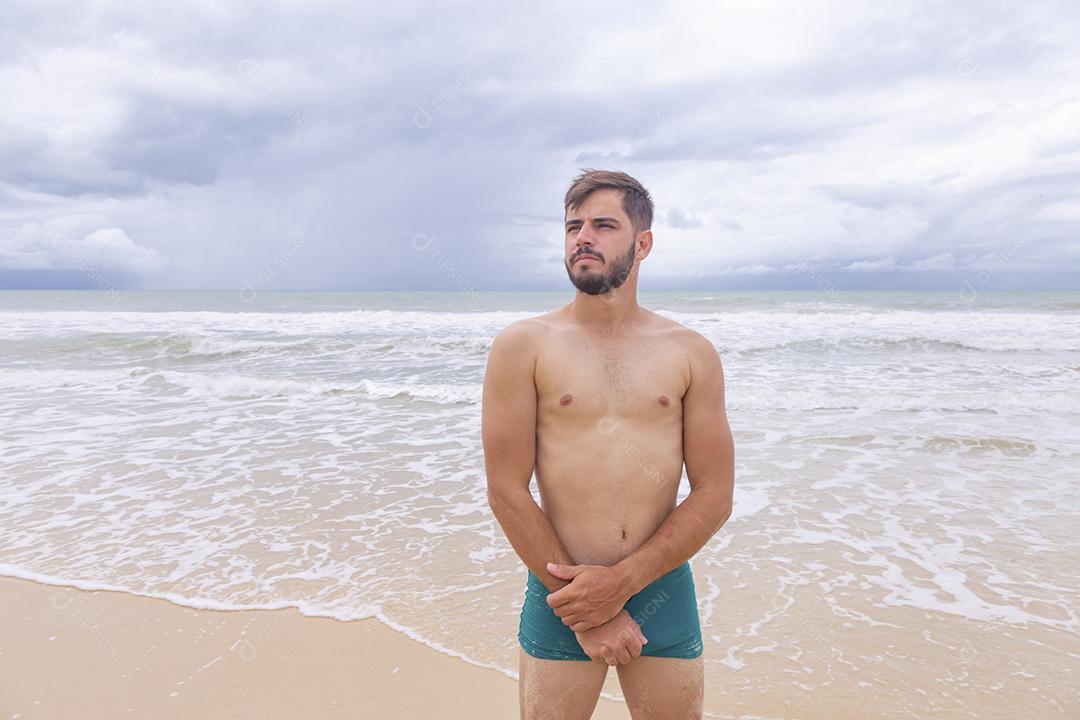 Homem bonito feliz na praia de férias. Menino na praia sorrindo para a câmera