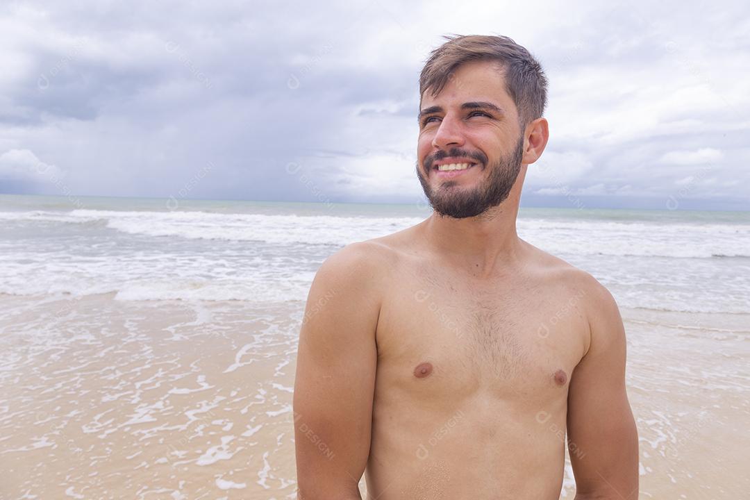 Homem bonito feliz na praia de férias. Menino na praia sorrindo para a câmera