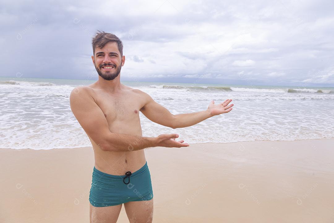 Homem bonito feliz na praia de férias. Menino na praia sorrindo para a câmera