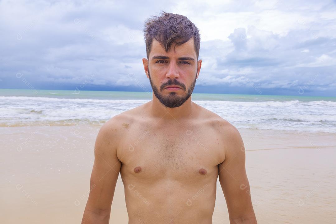Homem bonito feliz na praia de férias. Menino na praia sorrindo para a câmera
