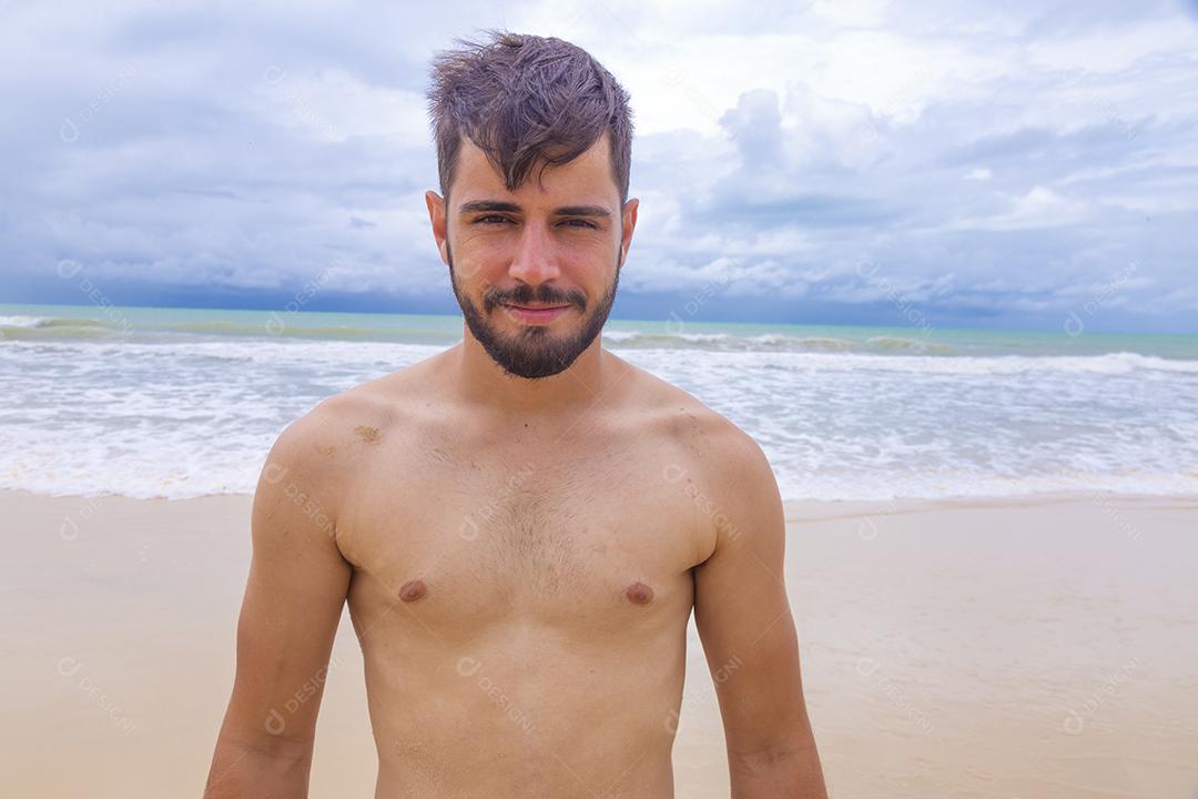 Homem bonito feliz na praia de férias. Menino na praia sorrindo para a câmera