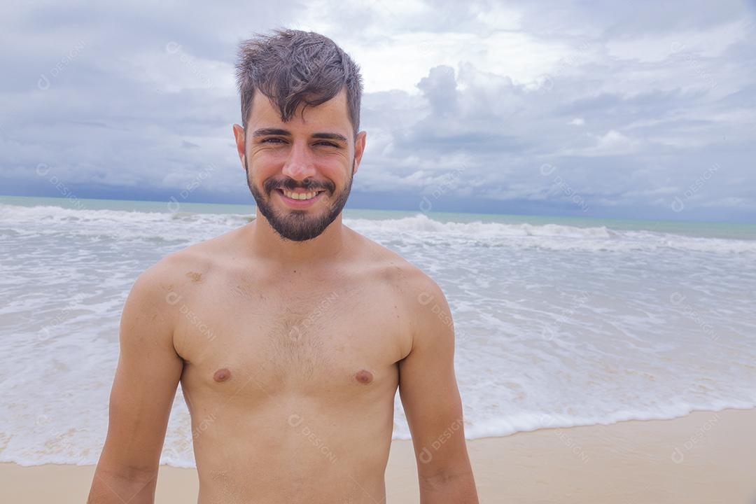 Homem bonito feliz na praia de férias. Menino na praia sorrindo para a câmera