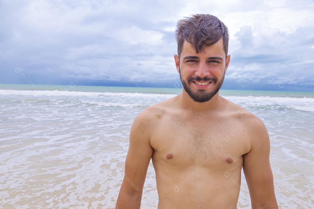 Homem bonito feliz na praia de férias. Menino na praia sorrindo para a câmera